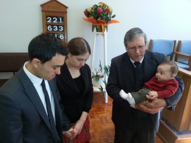 Pastor Matthias Thiel praying with Nadine, Domenic and baby Immanuel